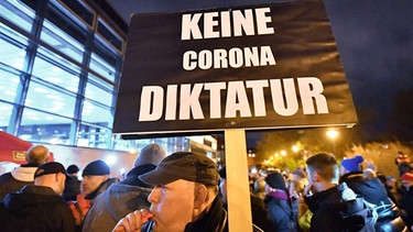 Querdenker-Demonstration: Mann pfeift in eine Trillerpfeife, trägt ein Schild: "Keine Corona-Diktatur" | Bild: picture alliance/dpa/dpa-Zentralbild | Martin Schutt