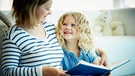 Eine Mutter liest mit ihrer Tochter auf dem Sofa ein Buch. Lesenlernen ist eine wichtige Voraussetzung dafür, dass Kinder erfolgreich lernen können. Wir erklären euch, wie ihr Kinder dabei unterstützen und fördern könnt. | Bild: colourbox.com/ Dmitrii Shironosov
