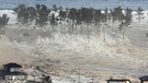 Nach dem schweren Erdbeben am 11. März 2011 bricht eine gigantische Tsunami-Welle über den Nordosten Japans herein, hier in Natori in der Präfektur Miyagi. | Bild: picture alliance / dpa | Aflo/mainichi Newspaper