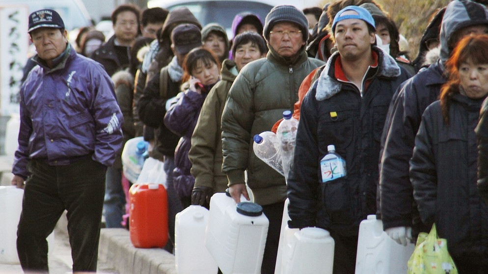 Nach dem schweren Erdbeben und verheerenden Tsunami am 11. März 2011 in Japan werden Lebensmittel und Trinkwasser knapp - darum stehen die Menschen in Schlange, mit Wasserkanistern in den Händen.  | Bild: picture-alliance/dpa