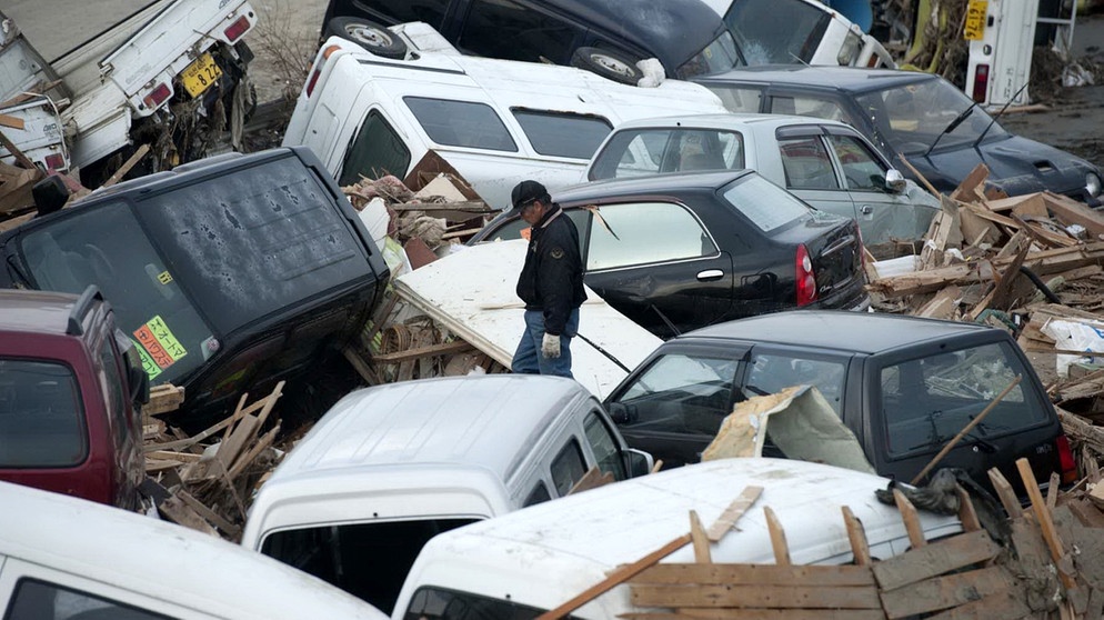 Zerstörte Autos türmen sich zwischen den Häusern von Sendai in den Straßen nach dem schweren Erdbeben und Tsunami vom 11. März 2011 im Nordosten Japans | Bild: picture alliance  dpa  Jhphoto