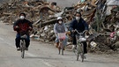 Radfahrer in Rikuzen Takata im Nordosten Japans nach dem schweren Erdbeben und Tsunami vom 11. März 2011. Starke seismische Aktivitäten und Verschiebungen tektonischer Platten können riesige Flutwellen, japanisch: Tsunamis auslösen. | Bild: picture alliance / NurPhoto | Seung-il Ryu