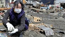 Eine Frau sucht in den Trümmern nach Geschirr ihres Restaurants, das im Tsunami weggerissen wurde, in Ofunato in der Präfektur Iwate im Nordosten Japans nach dem schweren Erdbeben vom 11. März 2011. Eine weitere Folge der Naturgewalt war die Nuklearkatastrophe von Fukushima. | Bild: picture alliance  dpa  Kimimasa Mayama