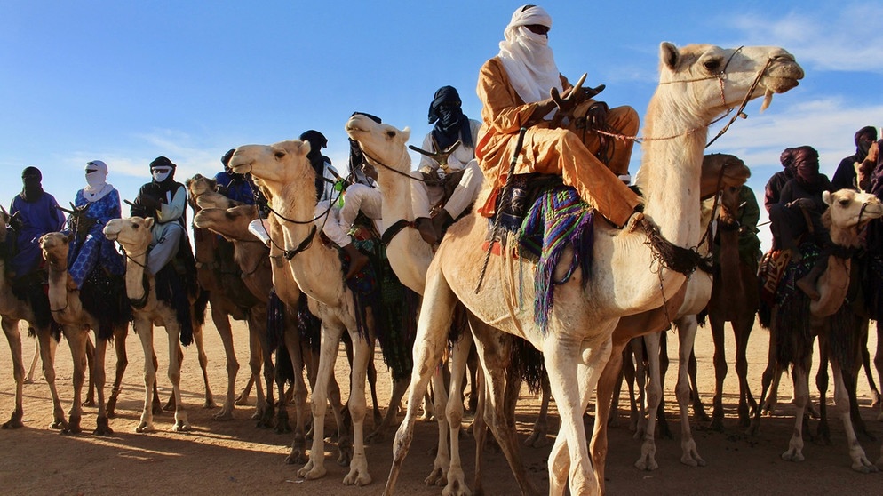 Tuaregs auf Kamelen im Niger. Bezieht man Halbwüsten mit ein, gehören den Wüsten mit rund 50 Millionen Quadratkilometern von allen Landschaftsformen der Erde die größte Fläche. Ein faszinierender und Lebensraum für eine besondere Tier-und Pflanzenwelt. Hier erfahrt ihr mehr über die trockensten Gebiete der Welt. | Bild: picture alliance/AP Photo | Ludivine Laniepce