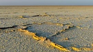 Eine Kruste aus Steinsalz bedeckt teilweise den Boden der Danakil-Wüste. Die Landschaften der Wüste der Erde sind weltweit unterschiedlich. Milliarden von Sandkörnern, Dünen, Schotterebenen, Felsgebirge, Salzseen und auch Eisflächen prägen die trockensten Gebiete der Welt. | Bild: picture alliance/Bildagentur-online/Fischer