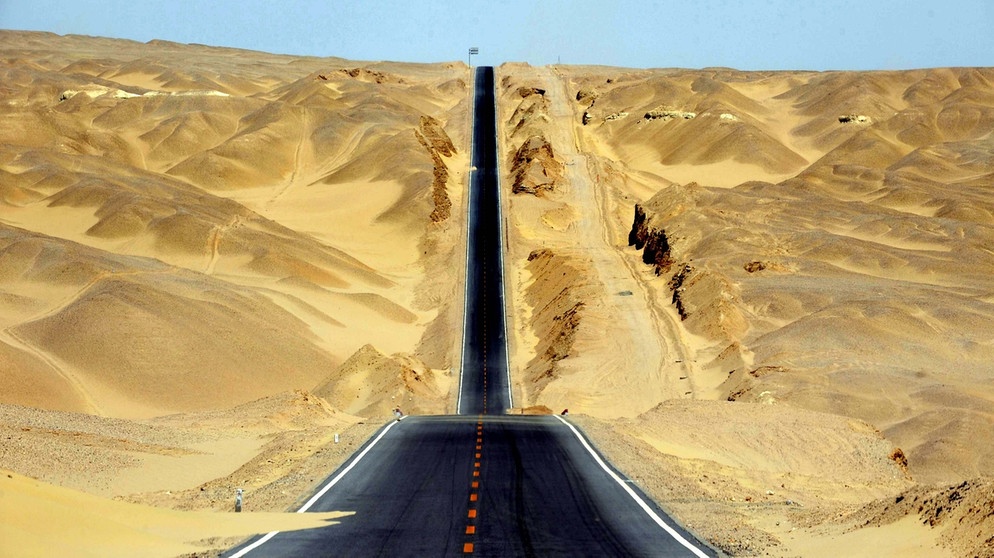 Straße durch die chinesische Qaidam-Wüste, einer Binnenwüste. Wie entstehen Wüsten? Und welche Wüstentypen gibt es weltweit? Wüsten sind ein trockener und faszinierender Lebensraum für eine besondere Tier- und Pflanzenwelt.  | Bild: picture-alliance/dpa