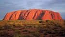 Uluru (Ayers Rock) in Australien - keine Wüste, sondern eine riesige Sandsteinformation. Bezieht man Halbwüsten mit ein, gehören den Wüsten mit rund 50 Millionen Quadratkilometern von allen Landschaftsformen der Erde die größte Fläche. Ein faszinierender Lebensraum für eine besondere Tier-und Pflanzenwelt. Hier erfahrt ihr spannende Fakten über die trockensten Gebiete der Welt. | Bild: picture-alliance/dpa