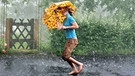 Frau mit Schirm läuft durch den Regen. - Vorsicht mit metallhaltigen Gegenständen bei Gewitter: Sie leiten Strom und können euch ernsthaft gefährden. | Bild: picture-alliance/dpa