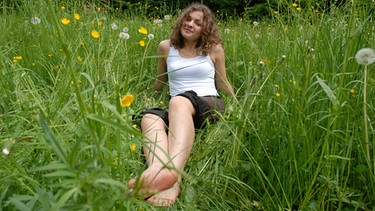 Frau sitzt in einer Blumenwiese | Bild: colourbox.com