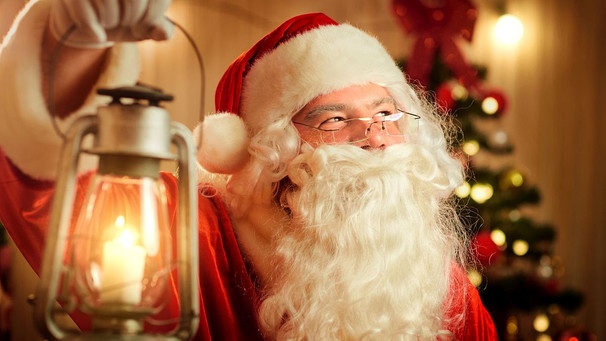 Nikolaus vor einem Christbaum hält eine Lampe in der Hand. | Bild: colourbox.com