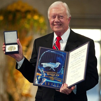 Der Friedensnobelpreisträger und frühere US-Präsident Jimmy Carter mit Urkunde und Medaille des Nobelpreises 2002 | Bild: picture-alliance/dpa