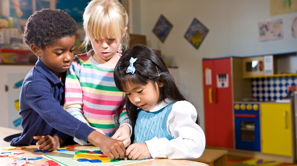 Kinder unterschiedlicher Herkunft spielen in einem Kindergarten, puzzeln.  | Bild: picture-alliance/dpa