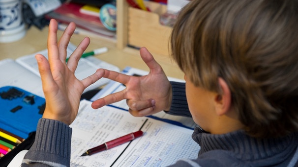 Ein achtjähriger Junge nimmt bei den Hausaufgaben im Fach Mathematik seine Finger zur Hilfe. | Bild: picture-alliance/dpa