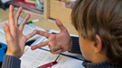 Ein achtjähriger Junge nimmt bei den Hausaufgaben im Fach Mathematik seine Finger zur Hilfe. | Bild: picture-alliance/dpa