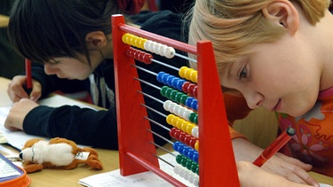 Schülerinnen lösen im Unterricht einer ersten und zweiten Klasse ihre Mathematikaufgaben. | Bild: picture-alliance/dpa