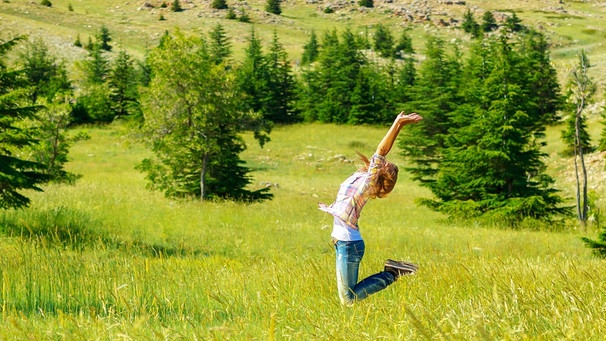 Junge Frau springt glücklich auf einer Wiese in die Luft | Bild: colourbox.com