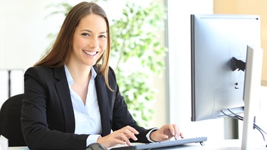 Ein wertschätzendes Umfeld und die Möglichkeit, die eigenen Interessen zu verfolgen steigern die Motivation bei der Arbeit. Eine junge Frau im Büro lächelt in die Kamera. | Bild: colourbox.com