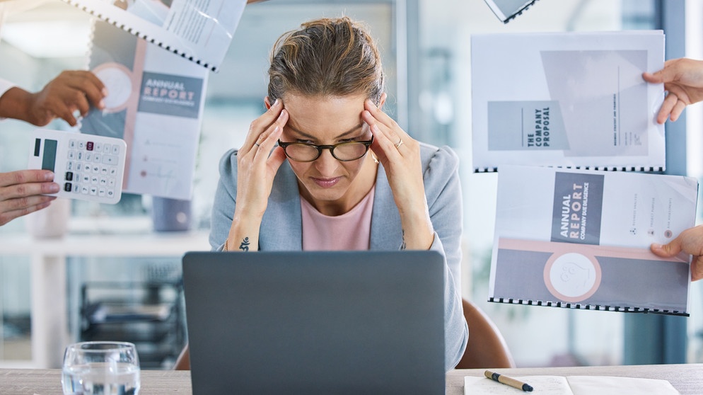Mehrere Hände reichen einer Frau Unterlagen. Multitasking kann zu Depressionen und Burnout führen.  | Bild: colourbox.com