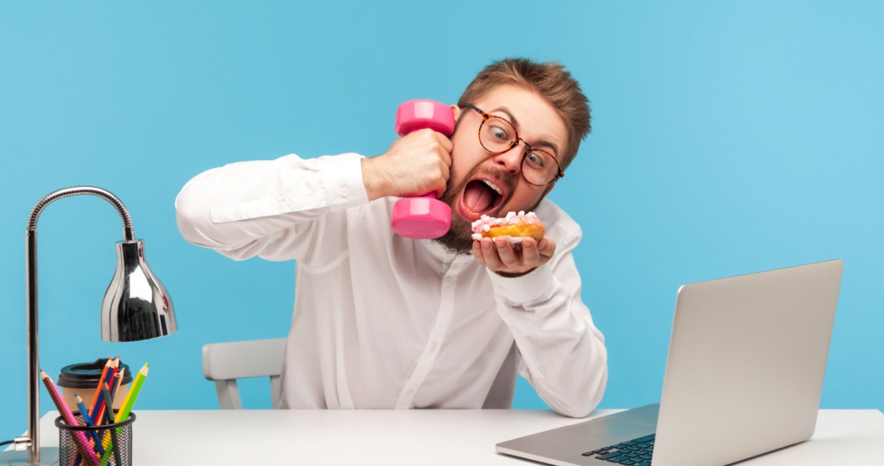 Zu viel Multitasking ist nicht gesund. Es verursacht Stress und kann auf Dauer zu einem Burnout oder zu einer Depression führen. Im Bild: Ein Mann sitzt am Schreibtisch vor dem Computer, hält in einer Hand eine Hantel in der andern ein Stück Kuchen. | Bild: picture alliance / Zoonar | Khosrow Rajab Kordi