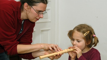 Lotte hat zu ihrem vierten Geburtstag eine Blockflöte geschenkt bekommen, und Mama bringt ihr nun die ersten Flötentöne bei. | Bild: picture-alliance/dpa