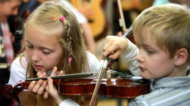 Kinder probieren im Rahmen des Programms "Jedem Kind ein Instrument" ihre neue Geige aus. | Bild: picture-alliance/dpa
