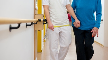 Eine an Demenz erkrankte Frau wird über den Flur in einem Pflegeheim geführt. | Bild: picture-alliance/dpa