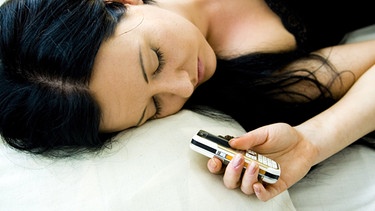 Schlafende Frau mit Mobiltelefon | Bild: picture-alliance/dpa