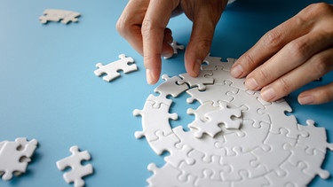 Zwei Hände puzzeln eine Schnecke. Hier erfahrt ihr, welche Formen von Perfektionismus es gibt, wann er krankhaft ist und wann er nützt.  | Bild: colourbox.com