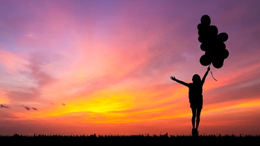 Mensch hält Luftballone in der Hand. Laut der Positiven Psychologie können wir Optimismus lernen. Wann sind Tipps zu mehr Zuversicht wirklich hilfreich und wann wird positives Denken toxisch?  | Bild: colourbox.com