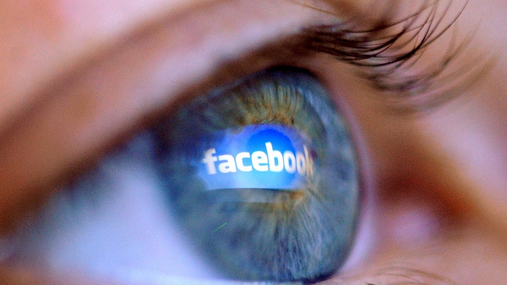 Der Schriftzug "Facebook" spiegelt sich im Auge einer jungen Frau. | Bild: picture-alliance/dpa