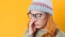 Eine müde wirkende junge Frau mit Brille und Mütze hält sich mit einer Hand die Augen zu. | Bild: colourbox.com