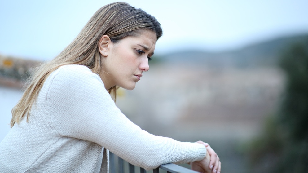 Junge Frau lehnt sich mit traurigem Gesichtsausdruck auf ein Geländer: Umgang mit der Trauer | Bild: colourbox.com