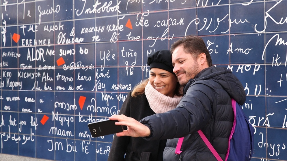 Ein Paar fotografiert sich vor der Je t'aime-Mauer im Pariser Künstlerviertel Montmarte.  | Bild: picture alliance/dpa | Olivier Boitet