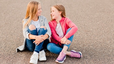Zwei Mädchen unterhalten sich auf dem Boden sitzend | Bild: picture alliance / Westend61 | Nicole Matthews