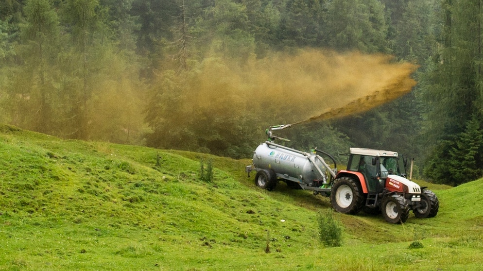 Ein Bauer mit Traktor bring Gülle auf einer Bergwiese aus. | Bild: picture alliance / photothek | Michael Gottschalk