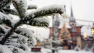 Symbolbild: Schneebedeckte Tanne vor Weihnachtskulisse. | Bild: dpa-Bildfunk/Matthias Bein