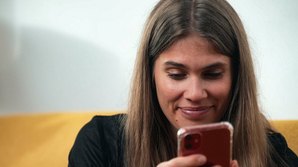 Ilka Knigge schaut auf ihr smartphone. In den Einstellung des handys kann man den CO2-Fußabdruck einsparen.  | Bild: BR