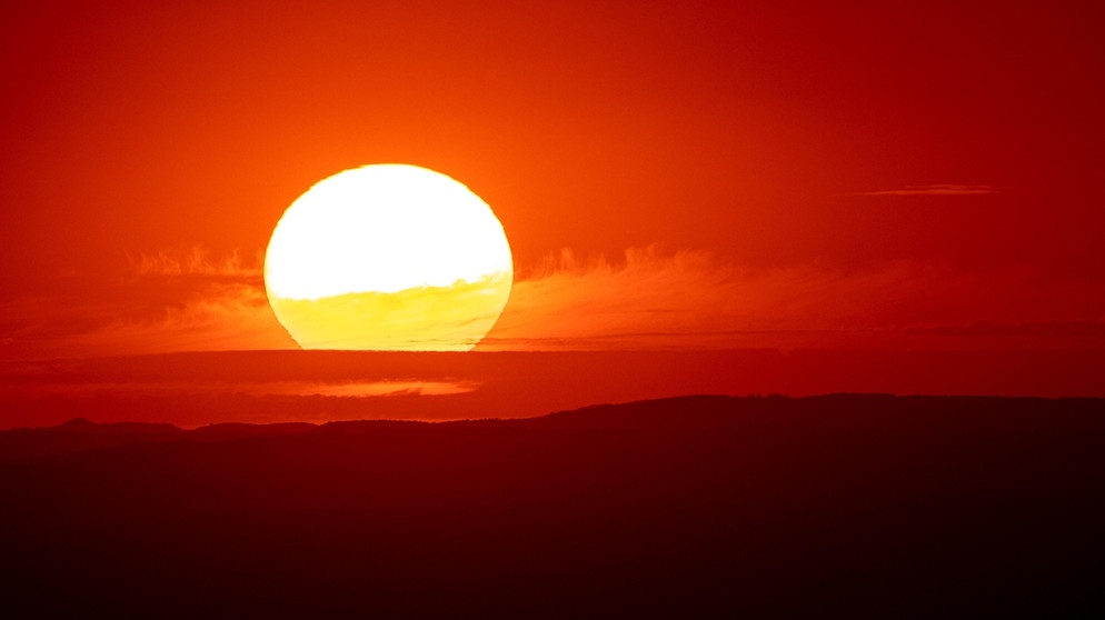 Die Sonne geht bei Schmitten in Hessen vom Großen Feldberg aus gesehen hinter den Hügeln am Horizont unter. Für die nächsten Tage ist eine Hitzewelle mit Temperaturen deutlich über 30 Grad vorhergesagt. | Bild: picture-alliance/dpa | Jan Eifert