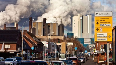 Eine Straße in Niederaussem mit Braunkohlekraftwerk im Hintergrund. | Bild: picture alliance / S. Ziese