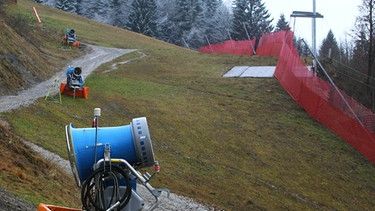 Schneekanonen auf der grünen Kandahar-Abfahrt in Garmisch-Partenkirchen im Dezember 2014. Schon jetzt ist der Winter in Bayern oft so mild, dass es an Schnee mangelt. Durch den fortschreitenden Klimawandel hat die Schneedeckendauer in Bayern bereits merklich abgenommen. | Bild: picture-alliance/dpa