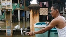 Mann schiebt Fahhrad durch überschwemmte Straße | Bild: picture-alliance/dpa