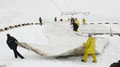 Männer legen Plastikplane über den Schnee | Bild: picture-alliance/dpa