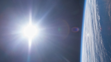 Links im Bild ist die Sonne zu sehen, rechts davon die Erde mit der Atmosphäre als dünne Schicht. Aufgenommen wurde das Bild von der Internationalen Raumstation ISS, die sich in einer niedrigen Erdumlaufbahn befindet.  | Bild: NASA/Terry Virts