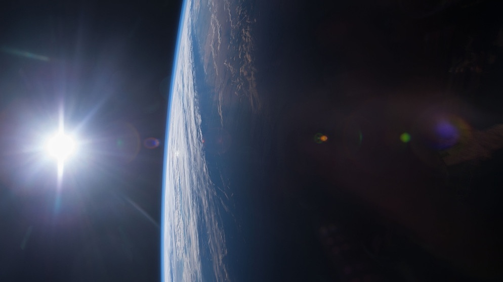 Links im Bild ist die Sonne zu sehen, rechts davon die Erde mit der Atmosphäre als dünne Schicht. Aufgenommen wurde das Bild von der Internationalen Raumstation ISS, die sich in einer niedrigen Erdumlaufbahn befindet.  | Bild: NASA/Terry Virts