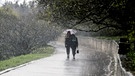 Auf diesem Bild regnet es, so viel ist klar: Die zwei Spaziergänger brauchen einen Regenschirm. Aber wie entsteht Regen eigentlich, und was ist der Unterschied zu Niederschlag?  | Bild: picture alliance / Photoshot | -