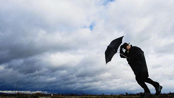Mann kämpft mit Schirm gegen den Wind: Der Wind ist ein Wettertreiber. Der Wind beeinflusst er das Wetter, so viel ist klar. Er lässt die Sonne scheinen und treibt die Wolken an. Doch wie entstehen die Winde überhaupt? | Bild: picture-alliance/dpa