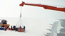 Der Bordkran des deutschen Forschungseisbrechers "Polarstern" hievt am 7.2.1999 Fässer mit Treibstoff von der Schelfeiskante der Antarktis auf das Deck. | Bild: Hans-Christian Wöste / Alfred-Wegener-Institut (AWI)