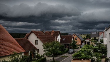 Bamberg, Deutschland 29. Juni 2021: Ein schweres Unwetter mit dunklen Wolken rollt auf Bamberg zu. Am Himmel sind dunkle Gewitterwolken zu sehen, der Vordergrund des Bildes zeigt ein Wohngebiet. | Bild: picture alliance / Fotostand | Fotostand / K. Schmitt