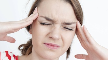 Wetterfühlige Frau hat Migräne Kopfschmerz. Sie hält sich die Hände an die Schläfen und kneift die Augen fest zu. | Bild: picture-alliance/dpa