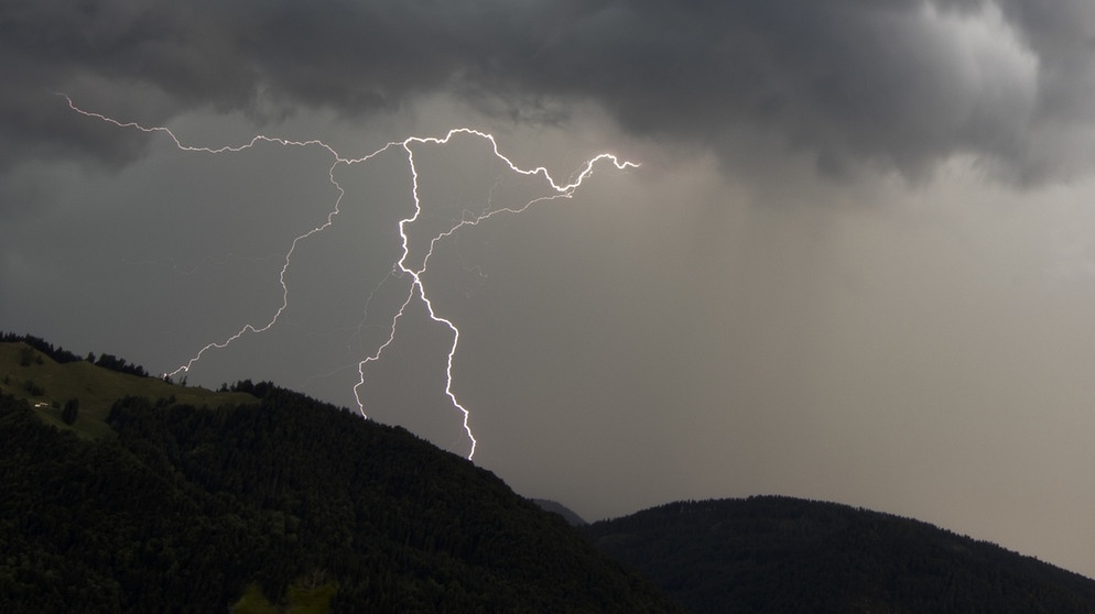 Ein Gewitter im Gebirge, mit einem Blitz. Wetterumschwünge können wetterfühligen Menschen Schmerzen und andere Beschwerden bereiten. | Bild: picture-alliance/dpa